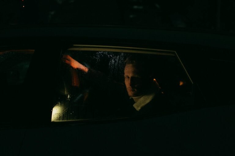 A mysterious man gazes through a rainy car window in low light.