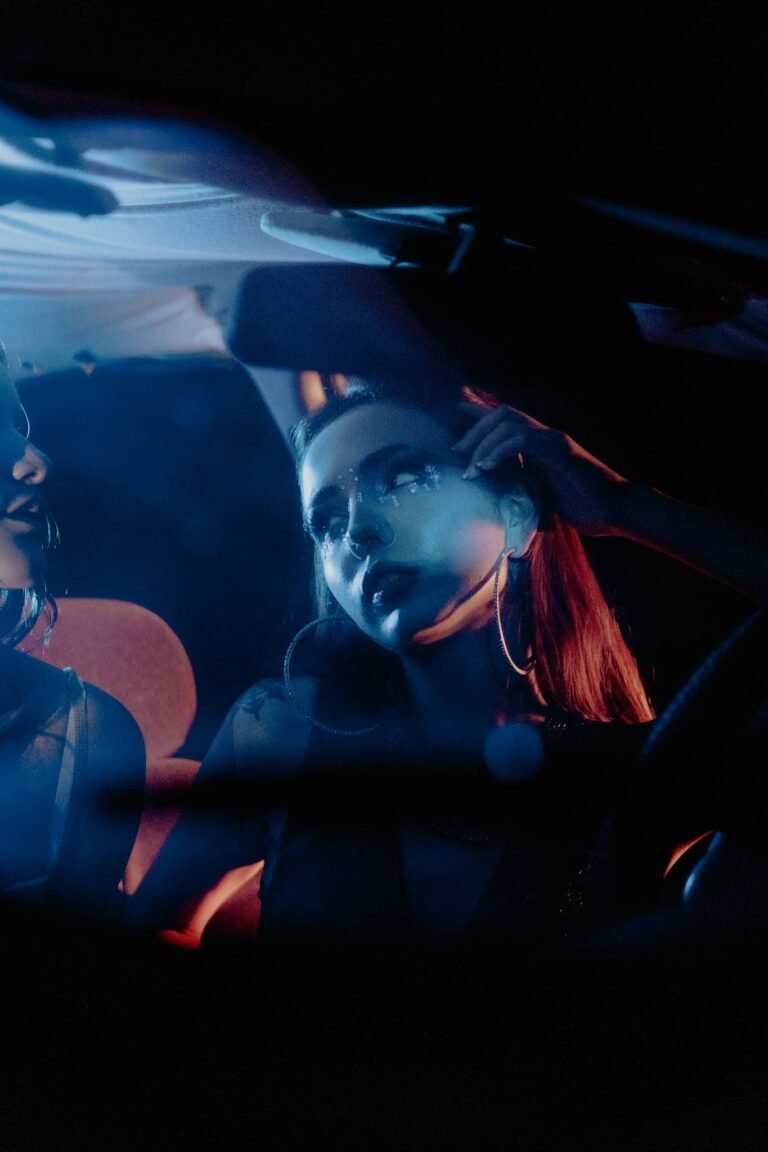 Artistic shot of a woman in a car with blue and red lighting, exuding a moody vibe.